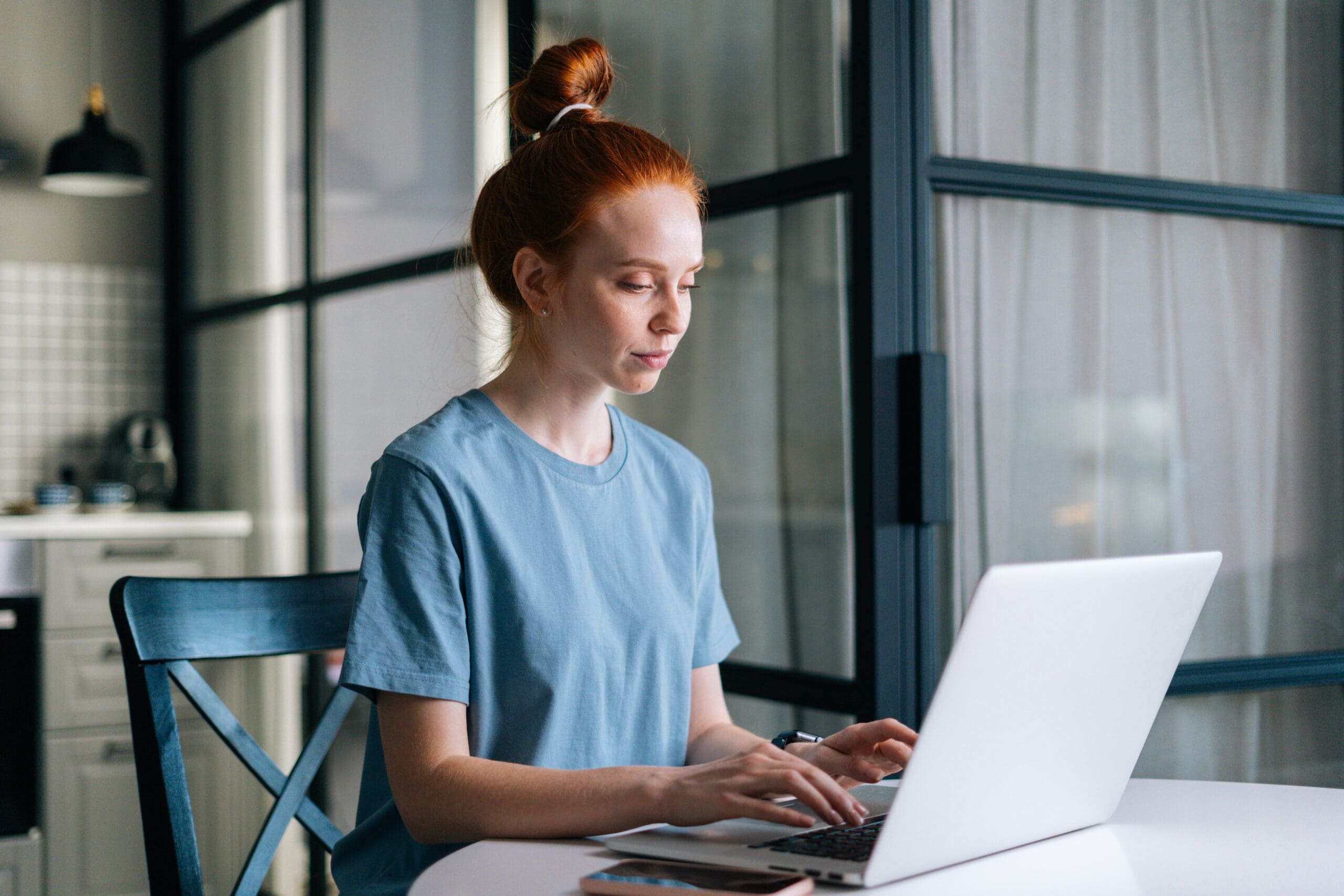 A red-haired woman sitting at her computer using ChatGPT as a therapist.