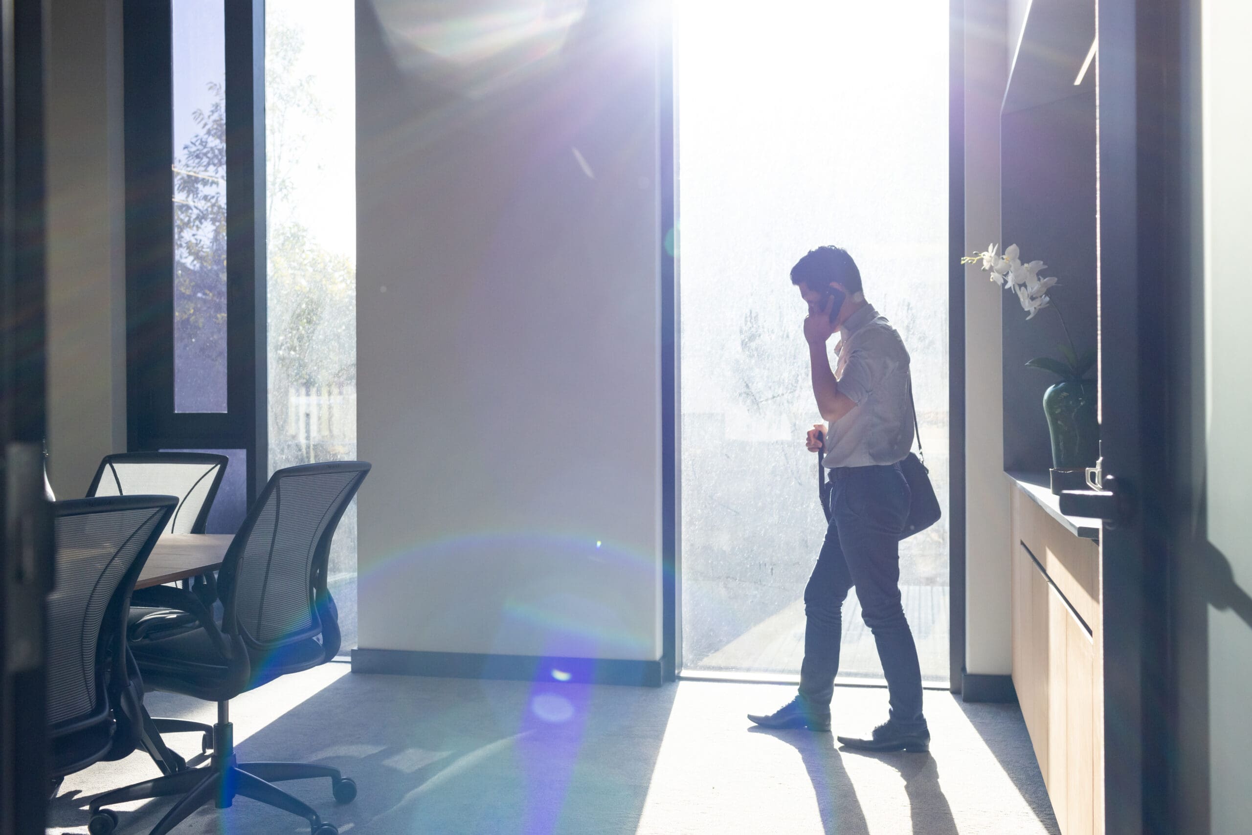 Walking man on phone experiencing imposter syndrome.